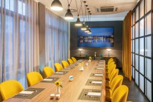 a conference room with a long table and yellow chairs at NH Hamburg Altona in Hamburg