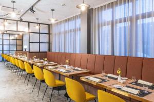 a dining room with long tables and yellow chairs at NH Hamburg Altona in Hamburg