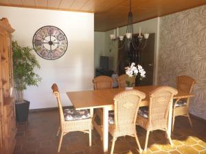 a dining room table with chairs and a clock on the wall at 10 Bett Ferienwohnung Sonnenblume in Wengenroth