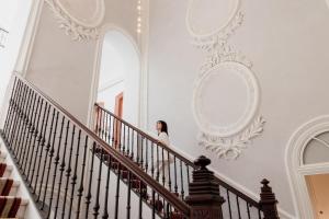 a woman walking down the stairs in a white house at Áurea Casa Palacio Sagasta by Eurostars Hotel Company in Cádiz