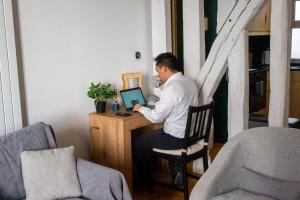 a man sitting at a desk with a laptop computer at Ômarais Guest House in Paris