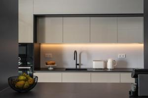 eine Küche mit weißen Schränken und einer Schale Obst in der Unterkunft Savoy Insular V by An Island Apart in Funchal + 66 Fotos