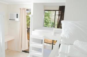 a bedroom with white bunk beds and a window at The Haven Hostel in Boracay +31 photos