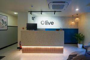 a lobby with a counter with a live sign on the wall at Olive Hotel Kundalahalli by Embassy Group in Bangalore