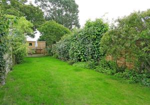 a garden with green grass and a fence at Seascape Luxury Cottage Southwold - Free Parking in Reydon
