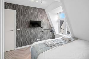 a bedroom with a bed and a tv on a wall at Unique Penthouse Near City Center And Park in Roosendaal
