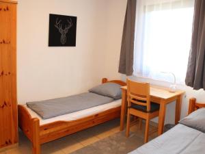 Ferienhaus Nr 93, Kategorie Komfort Plus, Feriendorf Hochbergle, Allgäu في Karlsebene: غرفة نوم بها سرير ومكتب ونافذة