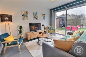 a living room with a couch and chairs and a tv at La nelliere 1 in Saint-Cast-le-Guildo