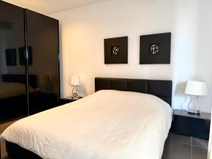 - une chambre avec un lit blanc et deux lampes dans l'établissement Sliema 1BDR Apartment with Pool Access and off Seafront, à Sliema