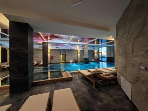 a pool in the middle of a room with tables and chairs at Apartman Aska - Residence Hill in Kopaonik