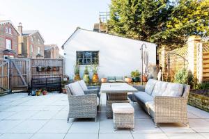 a patio with wicker furniture and a table and chairs at Veeve - Richmond on Canvas in Richmond upon Thames