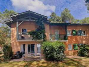 a house with a porch and a balcony at Petite Villa La Pantoufle au Domaine du Golf de Pinsolle in Soustons
