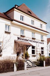 ミュンヘンにあるWürmtalhof Pension & Wirtshausの宿屋の暖炉を読む看板のある白い建物