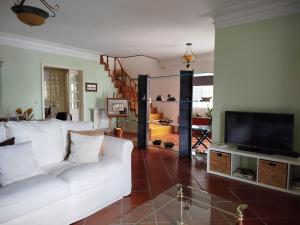 a living room with a white couch and a television at Casa Rua dos Loureiros in Marco de Canaveses