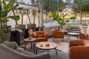 a lobby with chairs and tables and plants at Elba Almeria Business & Convention Hotel in Almería