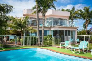 una casa con piscina delante de una casa en Beach Street Apartments, en Merimbula