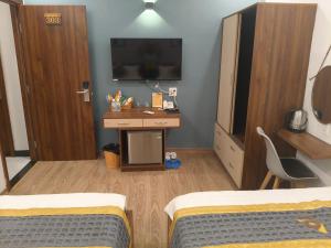 a room with two beds and a desk with a television at BaKa Hotel - Khách sạn Tuy Hòa in Liên Trì (3)