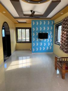 a large room with blue walls and a flat screen tv at Mangal Murti Family home stay in Alibaug