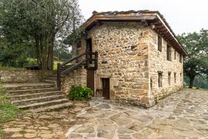 an old stone building with a wooden door and stairs at Cabaña Pasiega El Ojal B in San Pedro del Romeral