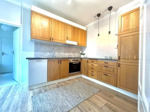 a large kitchen with wooden cabinets and a rug at Centralt och mysigt boende i Tomelilla in Tomelilla