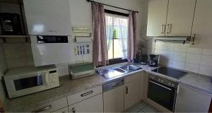 une cuisine avec un évier et un micro-ondes dans l'établissement Ferienhaus Nr 105, Kategorie Komfort, Feriendorf Hochbergle, Allgäu, à Karlsebene