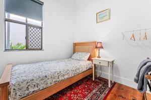 a bedroom with a bed and a table and a window at Character 1880s Renovated Cottage - Quiet location in Adelaide