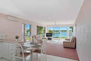 Una cocina y una sala de estar con mesa y sillas. en Beach Street Apartments, en Merimbula