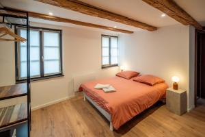una camera da letto con letto, lenzuola arancioni e finestre di Maison alsacienne a Sélestat