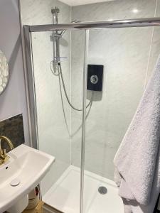 a shower with a glass door next to a sink at The Big Slepe in St. Ives +4 photos