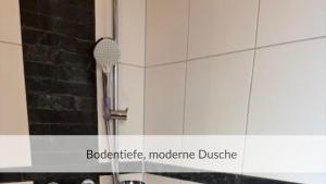 a shower in a bathroom with a black and white wall at Strandvilla Haffkrug Apartment Strandläufer in Scharbeutz +16 photos