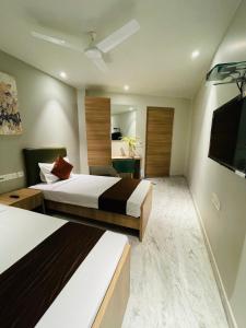 a hotel room with two beds and a flat screen tv at Hotel The Crest in Kolkata +8 photos