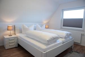 1 dormitorio blanco con 2 almohadas blancas y ventana en Deichhaus oben, en Norden