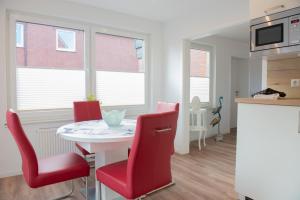 a kitchen and dining room with a table and red chairs at Deichhaus vorne in Norden