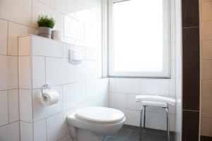 a white bathroom with a toilet and a window at Deichhaus vorne in Norden +1 photo