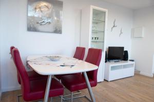 a dining room with a table and red chairs at Deichnähe - D in Norden