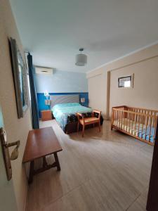 a bedroom with a bed and a crib in it at Tout près de la plage in Puerto de Sagunto