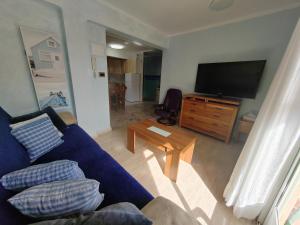 a living room with a blue couch and a television at Tout près de la plage in Puerto de Sagunto