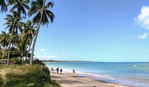a beach with palm trees and people on the beach at Casa Simples e Charmosa na Praia de Ipioca in Maceió