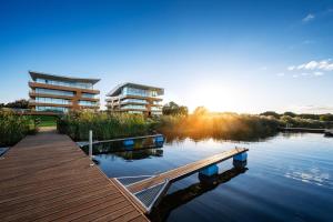 a dock on a lake in front of a building at Apartamenty prywatne przy Samej Wodzie w Riva Zegrze - Jezioro Zegrzyńskie in Zegrze Południowe