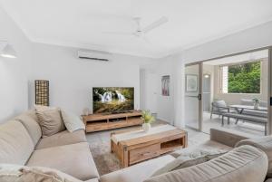 ein Wohnzimmer mit Sofa und Fernseher in der Unterkunft 2BR The Lakes Resort Escape, 4 Pools 5 min Airport in Cairns North