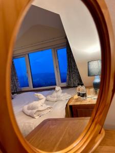 a mirror reflecting a bedroom with towels on a bed at Valley View Cottage by MaisonPro in Ebley