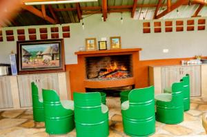 a living room with a fireplace and green chairs at Grevillea Farm house in Kamondo