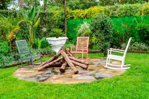 three chairs and a pile of logs in a yard at Grevillea Farm house in Kamondo +33 photos