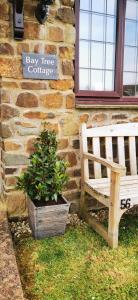 eine Holzbank vor einem Backsteingebäude in der Unterkunft Bay Tree Cottage - cosy home near beach in Woolacombe