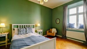 Un dormitorio con paredes verdes y una cama y una ventana. en Vintage apartments Floriańska street - By Hosty, en Cracovia