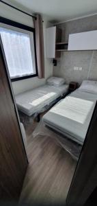 two beds in a room with a window at mh 6 pers ensoleillé Bois Masson in Saint-Jean-de-Monts
