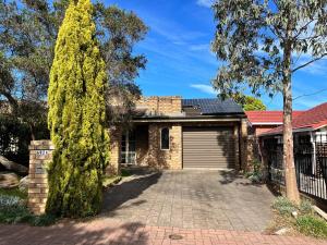 ein Backsteinhaus mit einer Garage und einem Baum in der Unterkunft Peaceful cottage Burnside area in Burnside