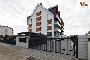 a white building with a fence in front of it at Ustronnie Residence Premium z mini Spa in Ustronie Morskie