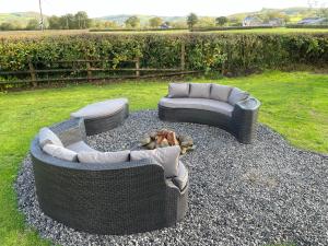 two wicker chairs and a couch sitting on gravel at The Pod at Gerycoed in Llangadog