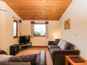 a living room with a couch and a tv at The Oak Lodge in Lyme Regis